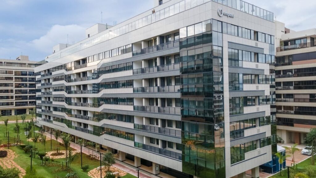 Fachada moderna de um prédio revestido em pele de vidro e granito, destacando as varandas de um Apartamento 3 Quartos Noroeste - Residencial Yard em Brasília.