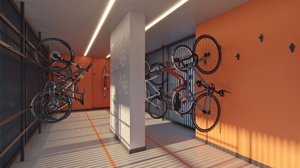 Área de bicicletário do Residencial Unité em Águas Claras, apresentando paredes laranjas, iluminação em trilhos de LED e bicicletas penduradas de forma organizada.